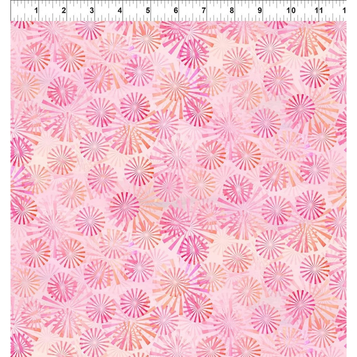 A pink patterned fabric swatch with a repeating radial sunburst motif in shades of pink, coral, and peach, shown with a white ruler at the top edge for scale.