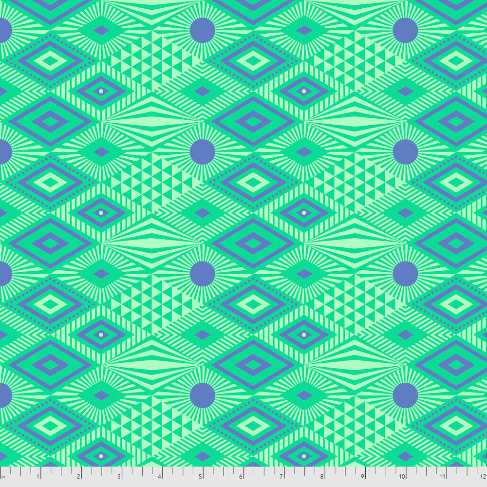Geometric pattern with indigo blue shapes on a green background with a ruler for scale