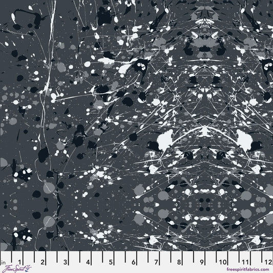 Abstract paint-splatter fabric pattern in charcoal grey, with scattered black and white splashes and drips. Ruler at the bottom for scale.