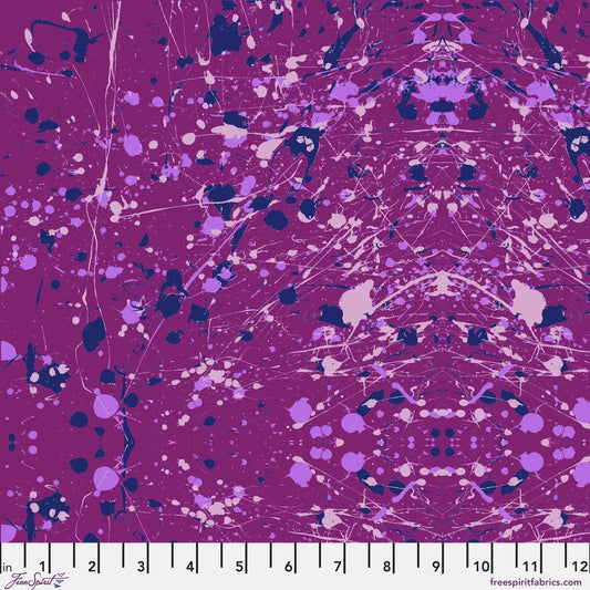 Abstract paint-splatter fabric pattern in bright purple, with scattered lavender and navy splashes and drips. Ruler at the bottom for scale.
