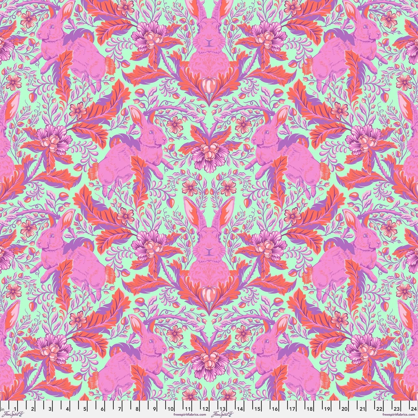 Patterned fabric with pink rabbits and flowers on a green background with a ruler for scale.