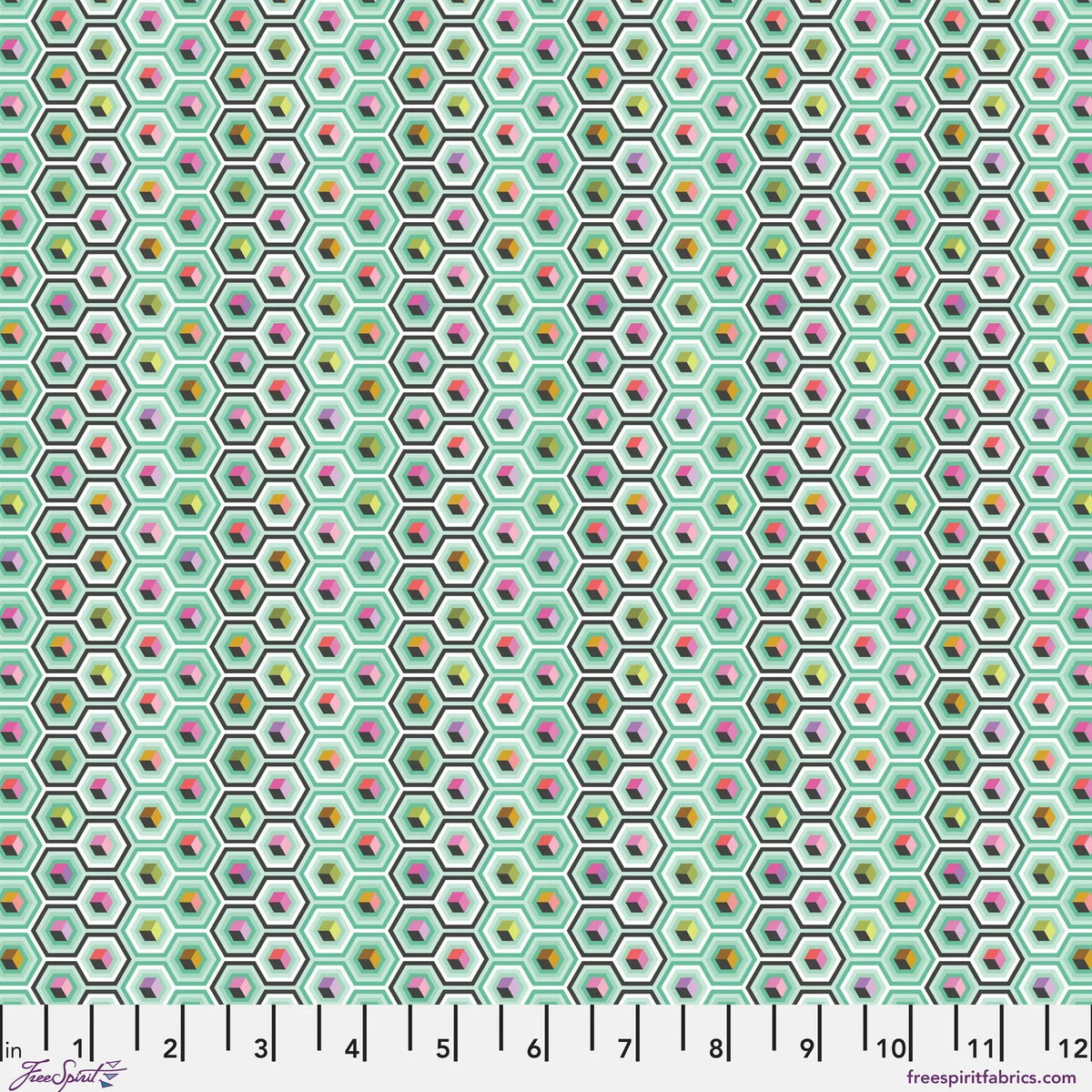 A repeating geometric fabric pattern of small hexagons on a mint green background, each containing colorful cube motifs in pink, yellow, orange, green, and purple. Ruler at the bottom for scale.