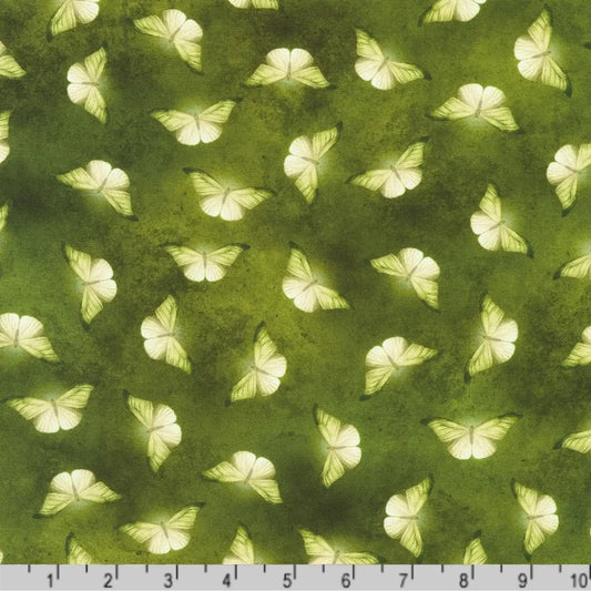 Patterned fabric of softly glowing white moth silhouettes scattered across a mottled olive and chartreuse-green background with a ruler at the bottom for scale.