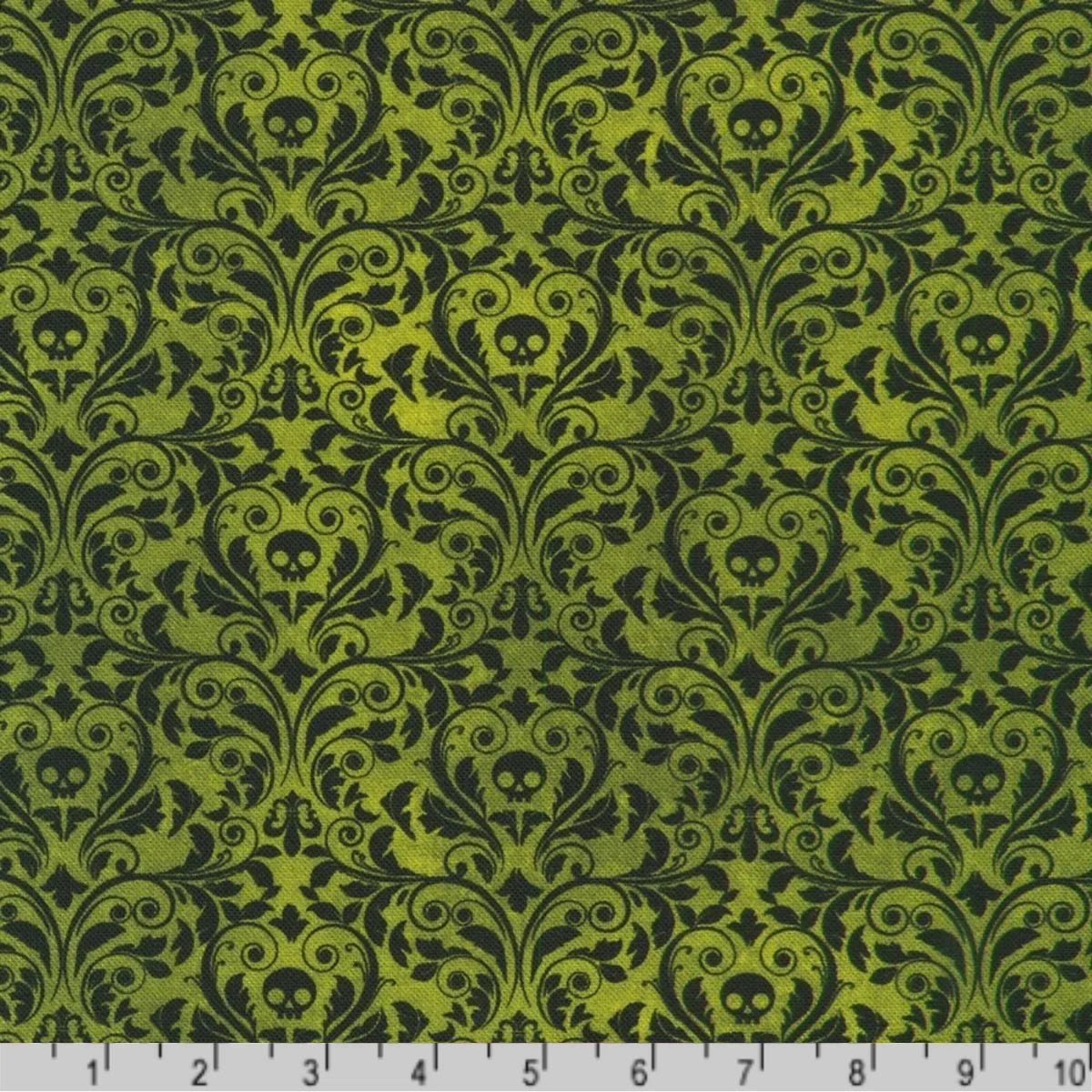 An ornate black damask pattern with small skull motifs on a rich forest-green background with a ruler at the bottom for scale.