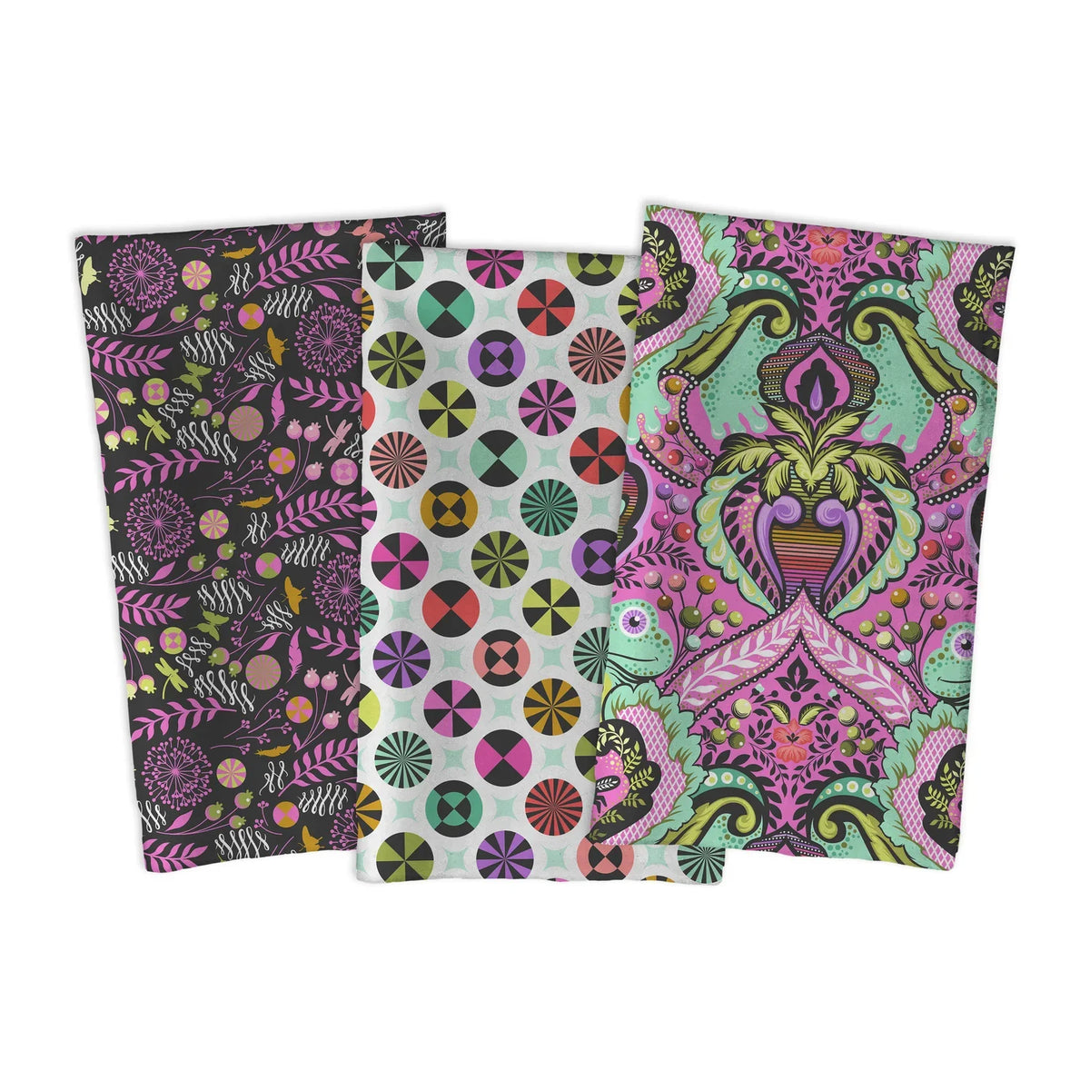 Three rectangular fabric pieces with colorful ornate patterns, arranged overlapping on a plain white background. The left piece has a dark floral and botanical print, the center piece has a white background with multicolored circular medallions, and the right piece has a large pink and green damask-style motif.