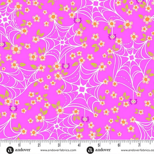 Fabric with spider webs and flowers on a pink background with a ruler for scale