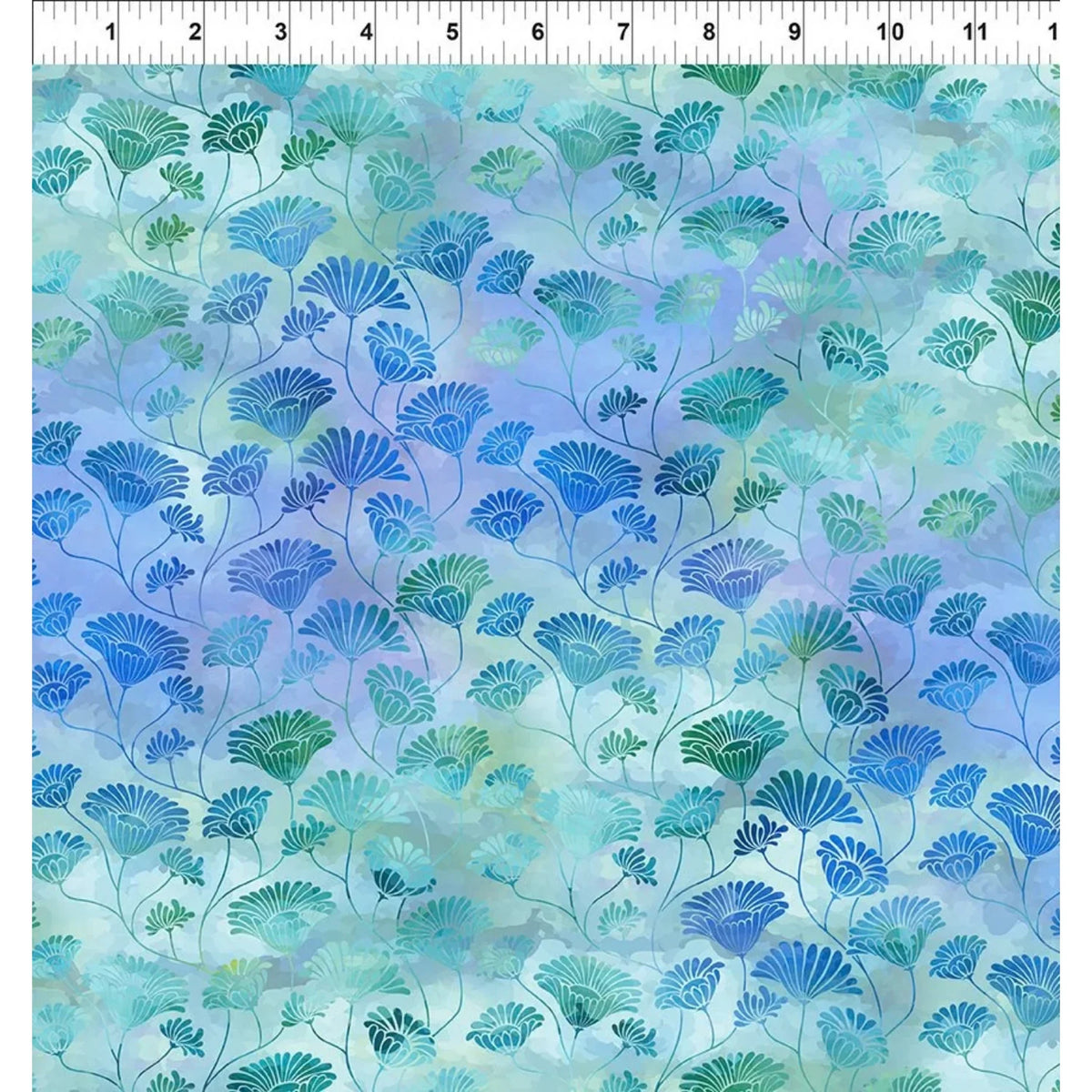 A fabric swatch with a repeating floral design in shades of blue, teal, and green over a soft aqua and periwinkle watercolor-like background. A white ruler along the top edge indicates scale.