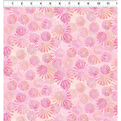 A pink patterned fabric swatch with a repeating radial sunburst motif in shades of pink, coral, and peach, shown with a white ruler at the top edge for scale.
