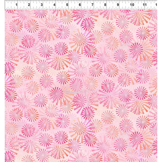 A pink patterned fabric swatch with a repeating radial sunburst motif in shades of pink, coral, and peach, shown with a white ruler at the top edge for scale.