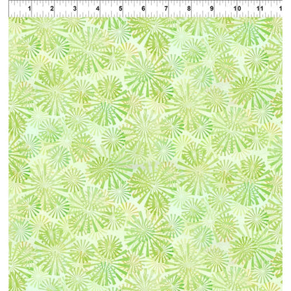 A fabric swatch with overlapping radial sunburst motifs in chartreuse and light-green on a spring green background. A ruler at the top edge indicates the scale of the print.