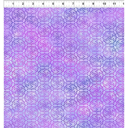 A fabric swatch featuring a repeating hexagonal pattern of tiny daisy-like petals in violet, periwinkle, and soft fuchsia with a white ruler along the top indicating scale.