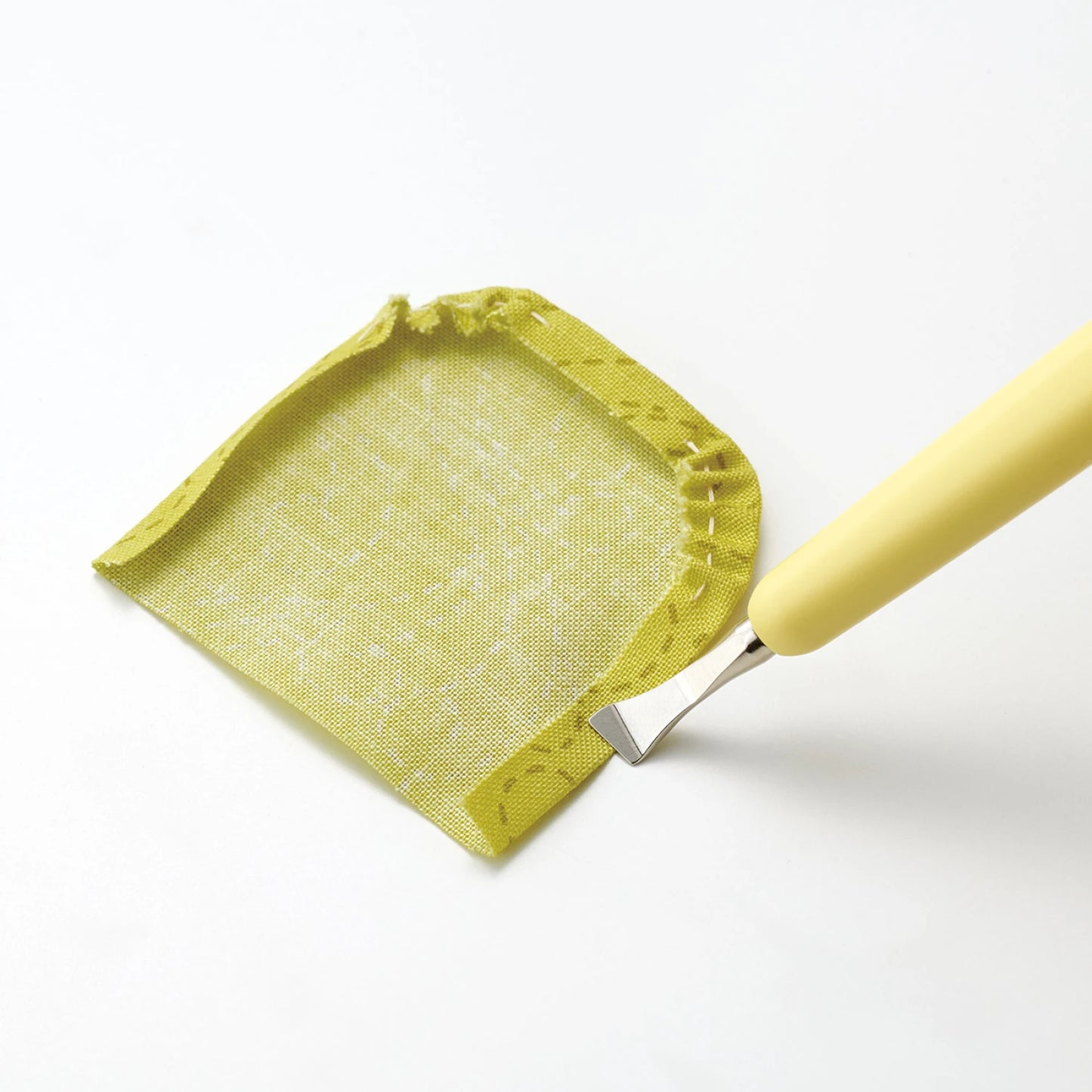 Yellow fabric applique piece with seams folded and creased by a Metal Hera tool