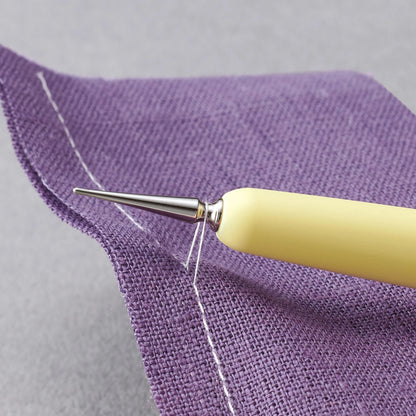 Yellow Hera tool lifting threads from purple fabric with a gray background