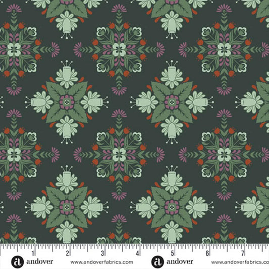 A repeating fabric pattern featuring a bold, symmetrical folk-art medallion design with intricate floral and leaf motifs in soft sage, purple, red, and cream on a deep forest-green background. Ruler at the bottom for scale.
