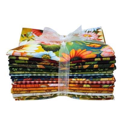 A stack of colorful fabric bundles tied together with a sheer white ribbon, featuring a vibrant floral and botanical print with sunflowers, daisies, and green leaves.