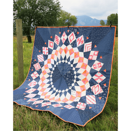 The Cadence Court Quilt made with pink, white, peach, and red wedges against a dark blue background.