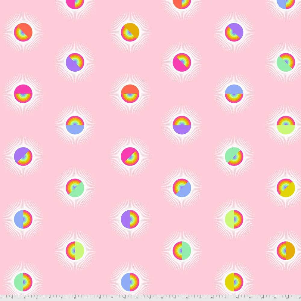 Pattern of colorful rainbow circles on a pink background with a ruler for scale