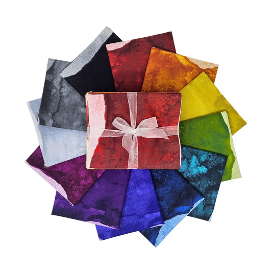 A circular arrangement of colorful fabric squares in many hues, with a bundle tied with a white ribbon placed in the center.