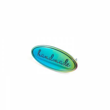 The "Handmade" Oval Metal Bag Label in Rainbow is iridescent and debossed with the word "Handmade" in a script font