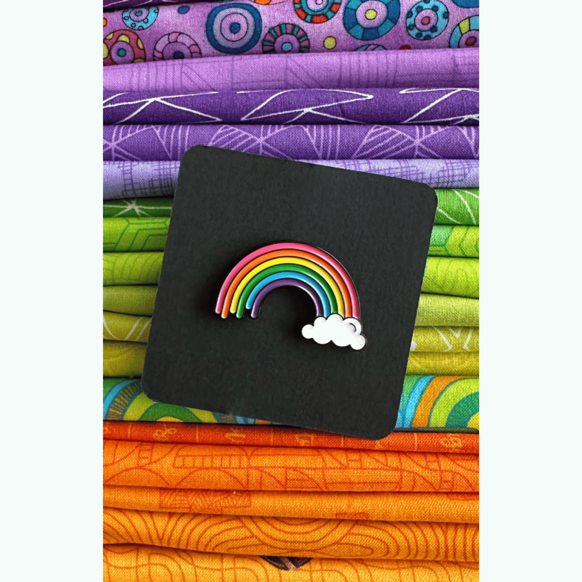 The Happy Highway Rainbow Enamel Pin features a curvy doodle of a rainbow sitting on a cloud on one side.