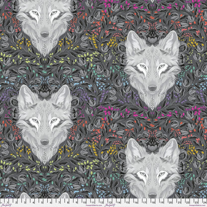Pattern of wolf faces surrounded by colorful foliage on a dark background with a ruler at the bottom for scale