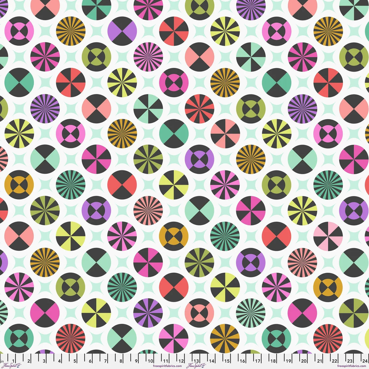 A repeating fabric pattern featuring colorful geometric medallions and pale mint-green star shapes on a white background, with a ruler along the bottom edge showing scale. 