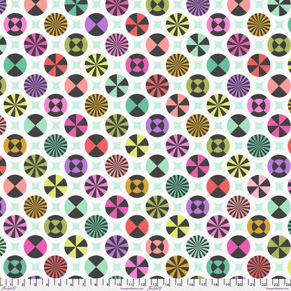 A repeating fabric pattern featuring colorful geometric medallions and pale mint-green star shapes on a white background, with a ruler along the bottom edge showing scale. 