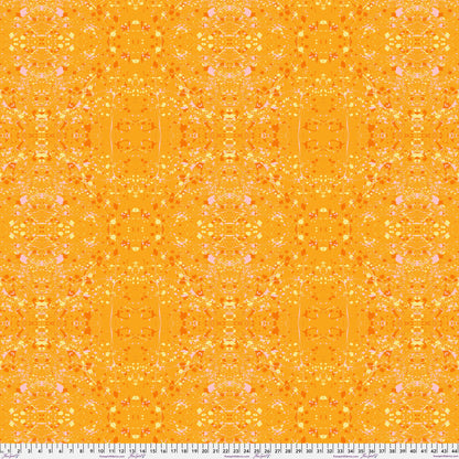 A seamless repeating fabric pattern featuring a symmetrical, kaleidoscopic design in vibrant orange, yellow, and soft pink tones. Ruler at the bottom for scale.