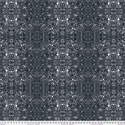 A seamless abstract fabric pattern featuring symmetrical, kaleidoscopic motifs in black, grey, and white, with a ruler at the bottom for scale.