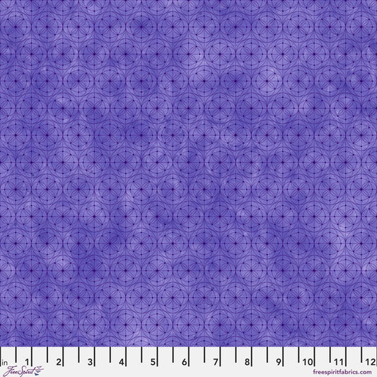 Purple fabric with a repeating geometric circle pattern, shown with a white ruler along the bottom edge for scale.