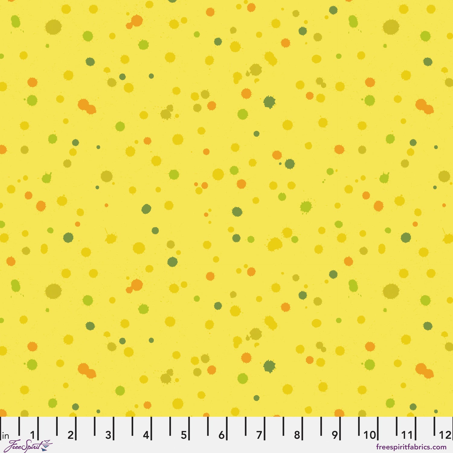 Fabric design of paint droplets in olive, orange, and chartreuse tones scattered across a warm, sunny yellow background. Ruler at the bottom for scale.