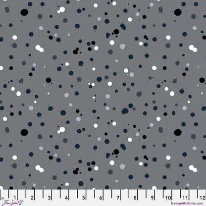 Fabric design with paint drops in black, white, and slate-grey tones scattered across a medium grey background. Ruler at the bottom for scale.