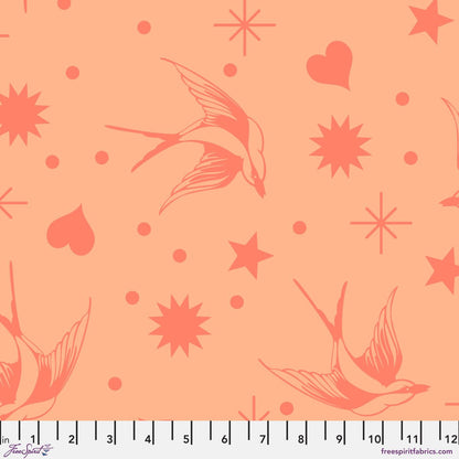 Neon Fairy Flakes in Lunar features coral pink swooping birds, stars, hearts, and dots tossed across a peach background. 12 inch ruler at the bottom for scale