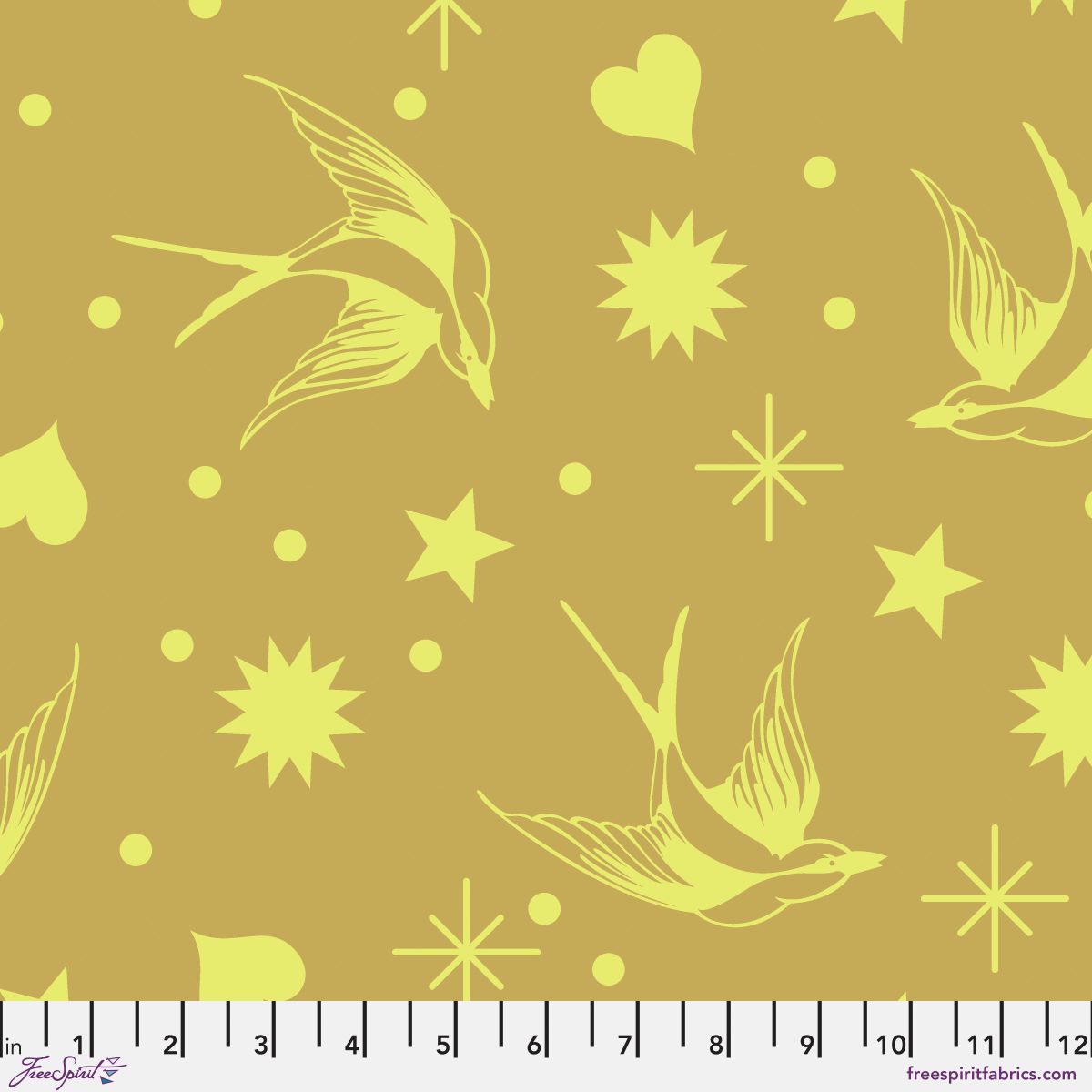 Neon Fairy Flakes in Moon Beam features yellow swooping birds, stars, hearts, and dots tossed across a gold background. 12 inch ruler at the bottom for scale