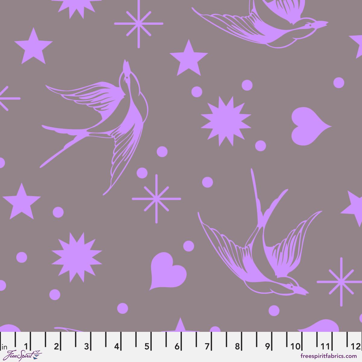 Neon Fairy Flakes in Mystic features purple swooping birds, stars, hearts, and dots tossed across a lavender-grey background. 12 inch ruler at the bottom for scale