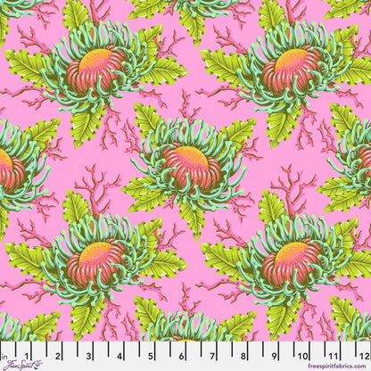 Pattern of large orange and pink sea anemone blooms with lime-green leaves on a bright pink background with a ruler for scale.