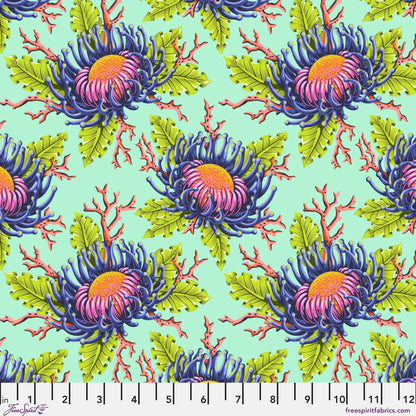 Pattern of large blue and pink sea anemone blooms with lime-green leaves on a bright aqua background with a ruler for scale.