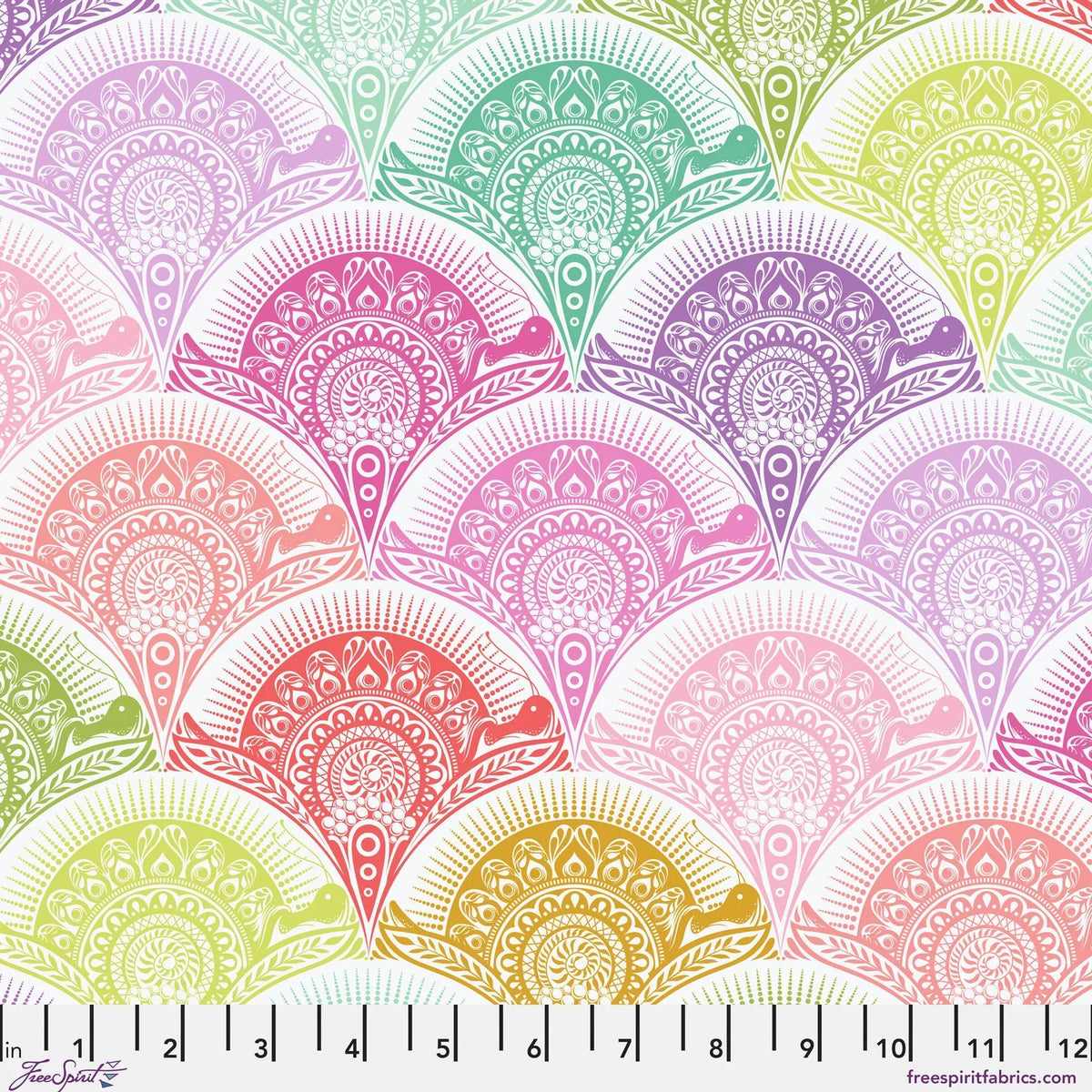 A repeating fabric pattern of ornate scalloped fan shapes in pastel rainbow colors on a white background, with a ruler along the bottom edge showing scale. 