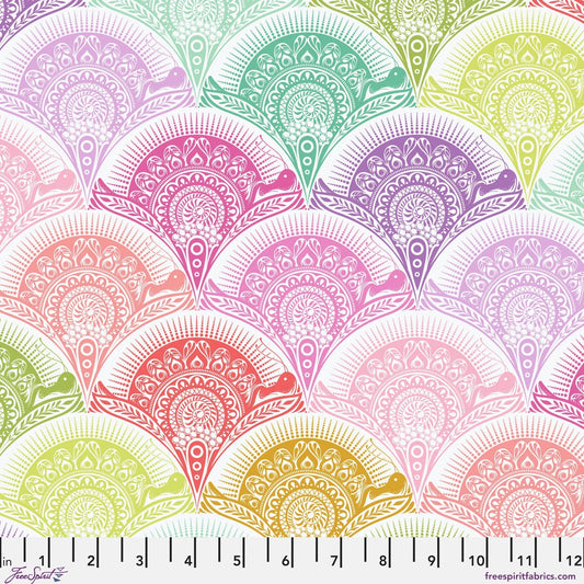A repeating fabric pattern of ornate scalloped fan shapes in pastel rainbow colors on a white background, with a ruler along the bottom edge showing scale. 