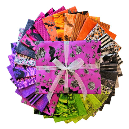 A fanned-out bundle of colorful fabric squares in vivid purples, oranges, greens, grays, and blacks, featuring floral designs, moths, spiderwebs, stripes, and abstract shapes with a One-Yard Bundle in the center.