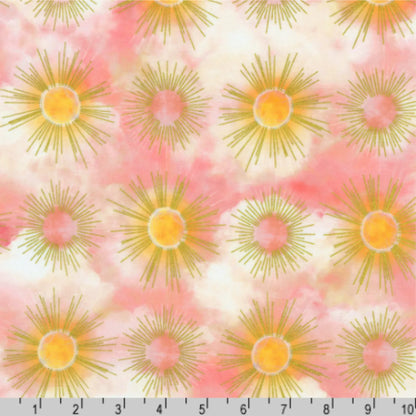 Pattern of sunburst designs with golden rays on a cloudy pink and off-white background with a ruler for scale