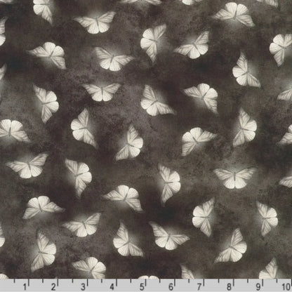 Patterned fabric of softly glowing white moth silhouettes scattered across a dark, mottled charcoal grey background with a ruler at the bottom for scale.