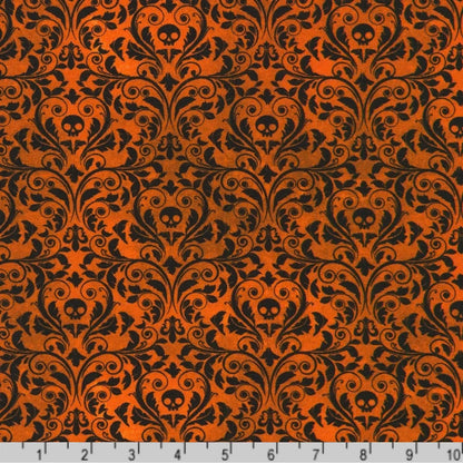 An ornate black damask pattern with small skull motifs on a warm, burnt-orange background with a ruler at the bottom for scale. 