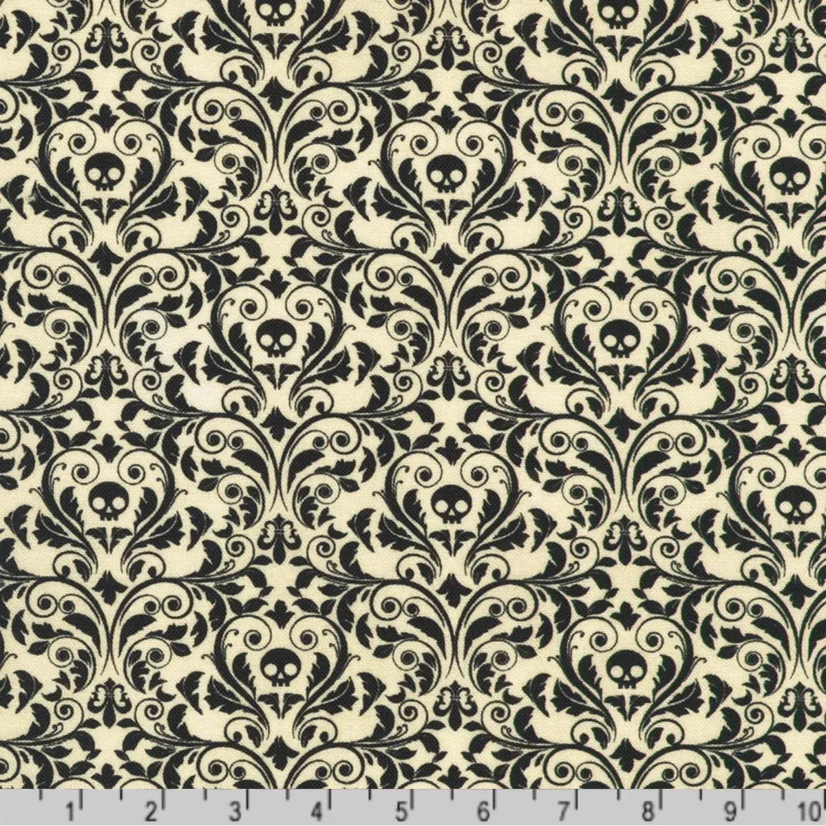 An ornate black damask pattern with small skull motifs on a soft, antique-white background with a ruler at the bottom for scale.