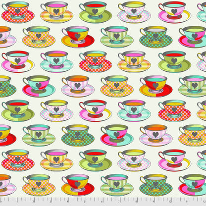 Pattern of colorful teacups and saucers on an off-white background with a ruler for scale