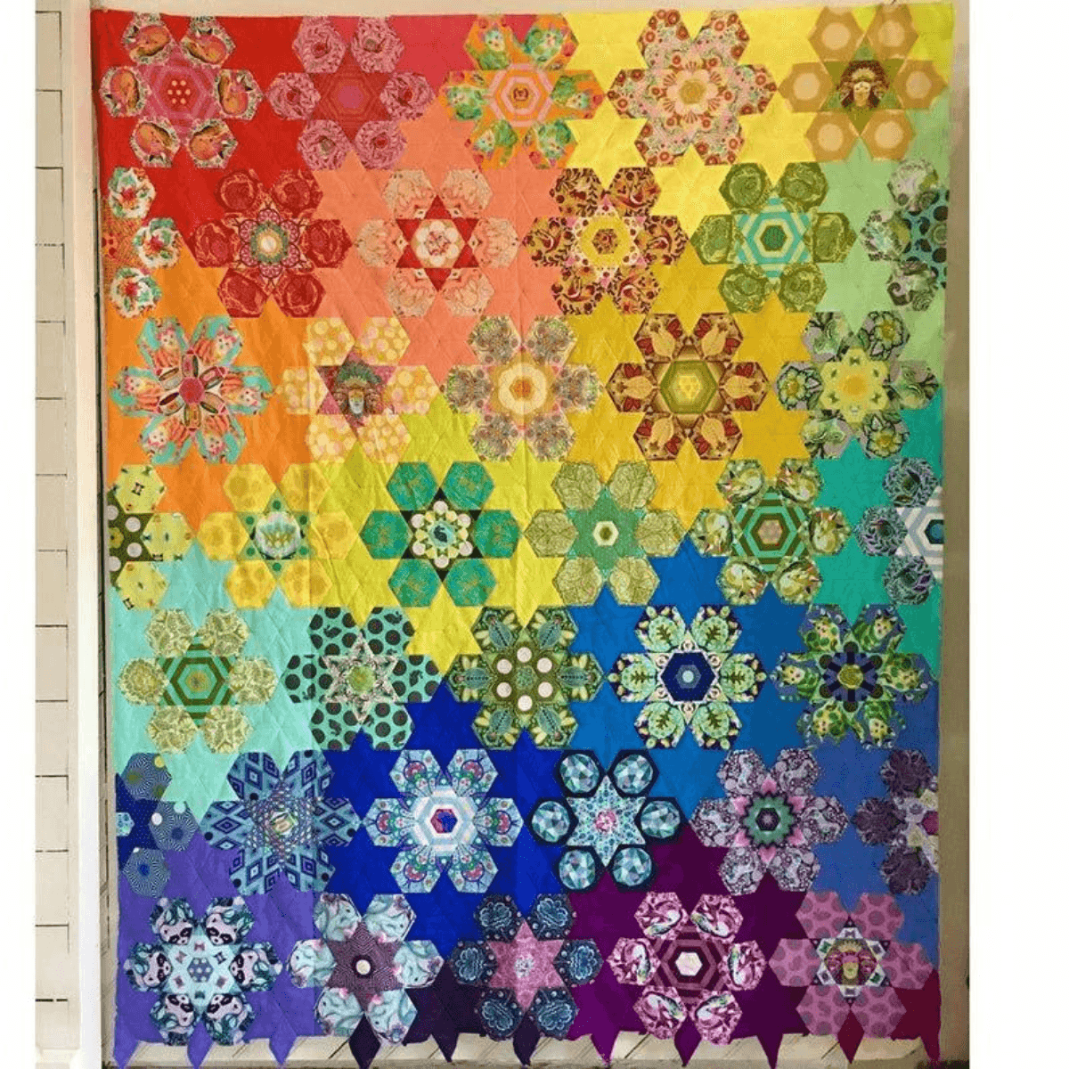 The Tula's Bloomers Quilt is an English Paper Pieced quilt using diamonds, hexagons, and pentagons to make colorful flower and star blocks. 