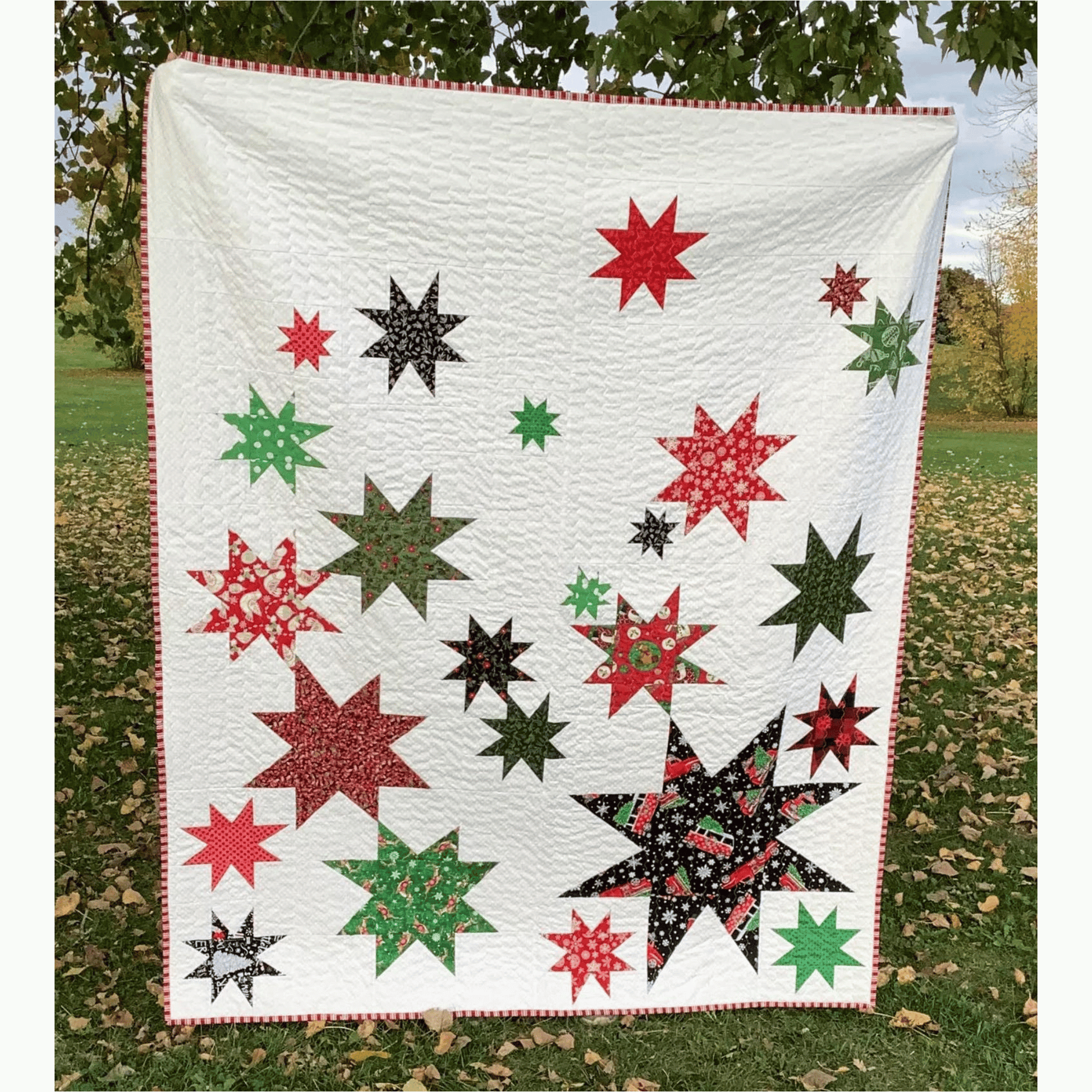 The Vela Quilt is a fun take on wonky stars. This modern quilt features various sized star blocks in red, black, and green Christmas prints pieced with a white background fabric.