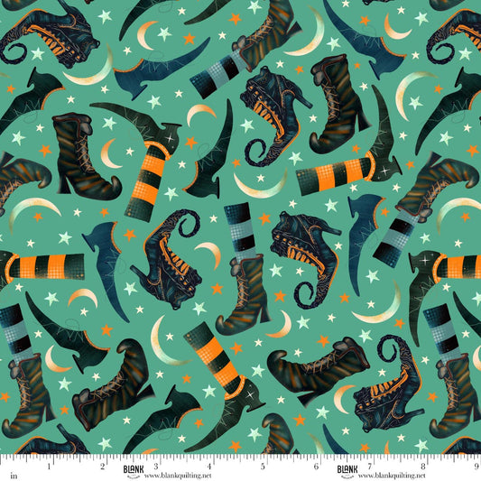 Pattern of witch boots, striped stockings, crescent moons, and stars on a teal background. Ruler for scale.